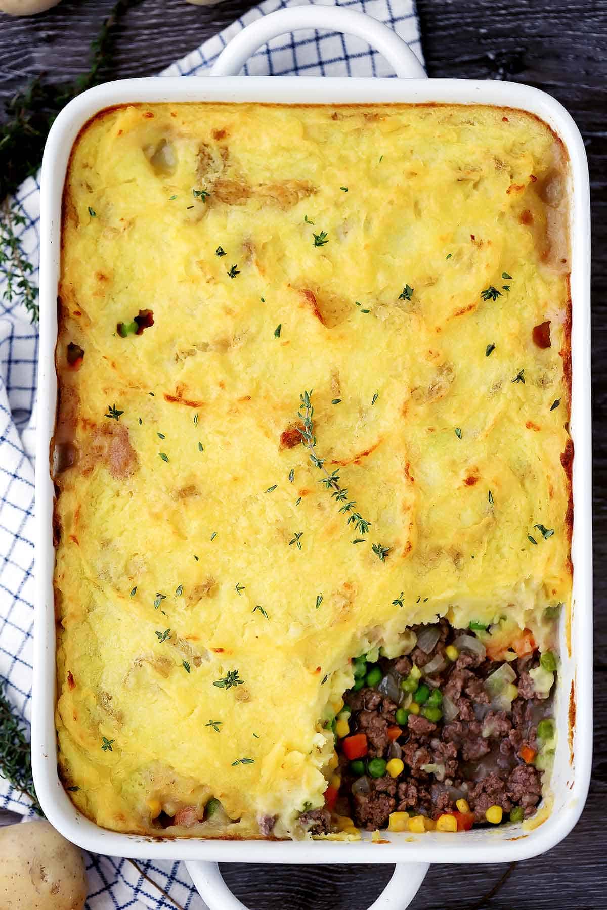 A large casserole dish with shepherd's pie and a sprig of thyme.