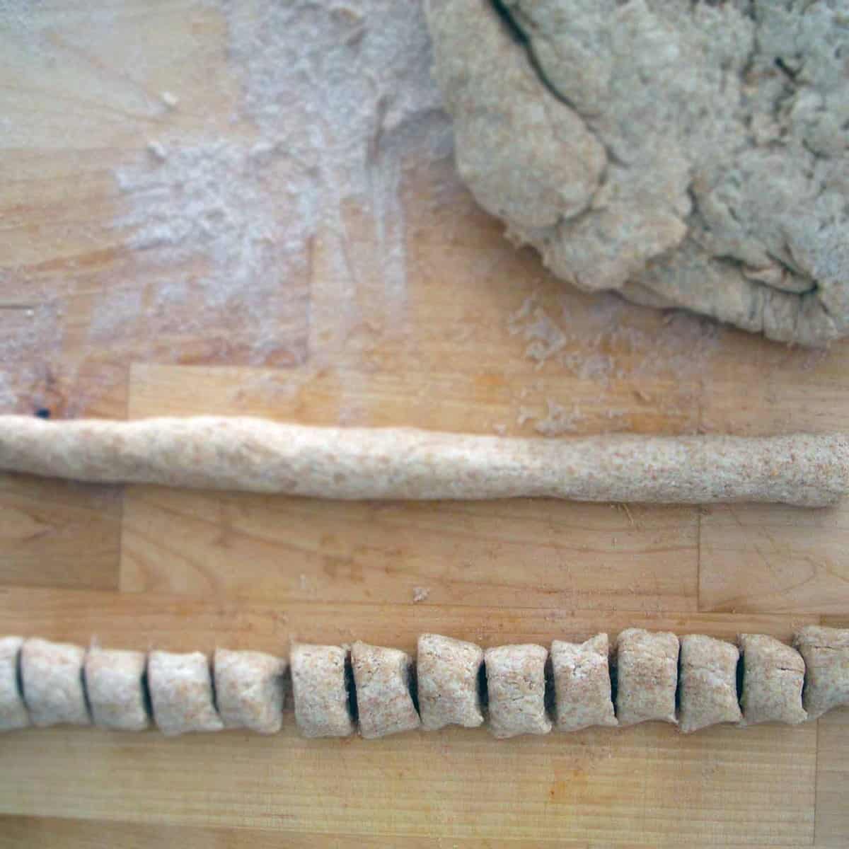 Whole wheat ricotta gnocchi rolled into a log, and rolled into a log and sliced into small pieces.