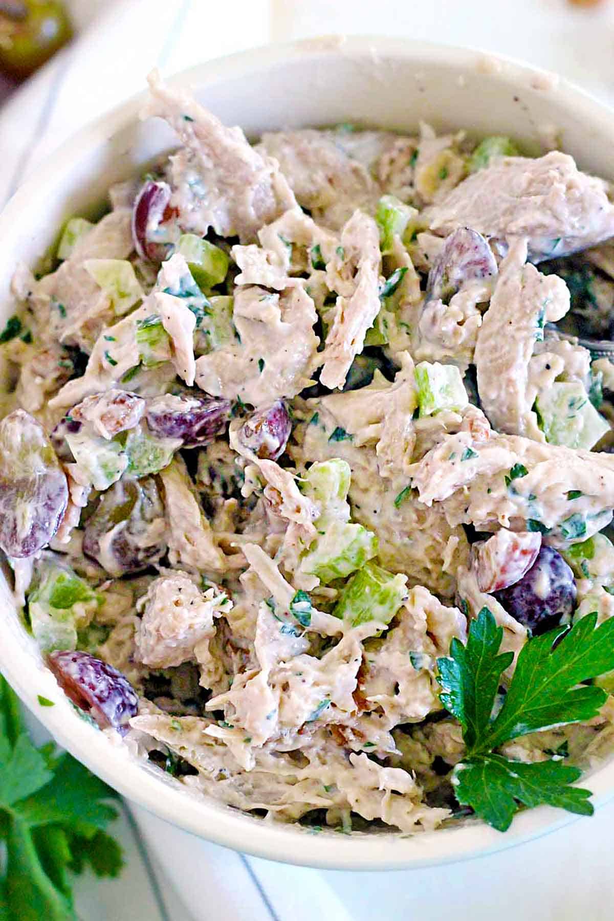 A bowl of chicken salad with grapes and walnuts.