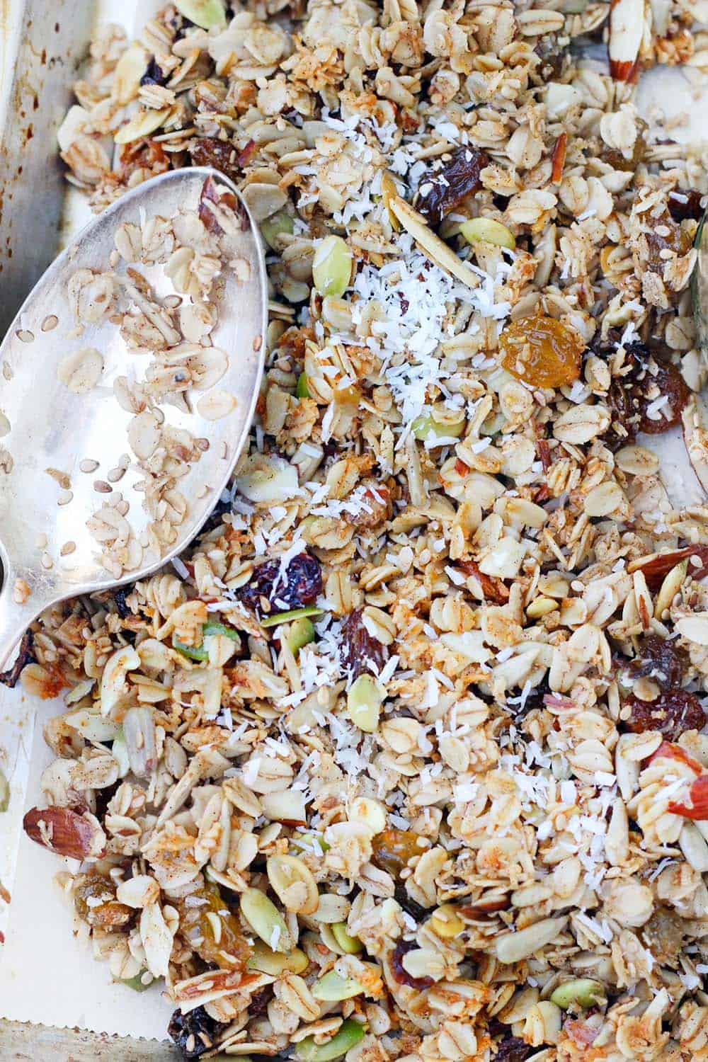 Close up bird's eye view of a layer of granola, with a silver antique spoon on the side.