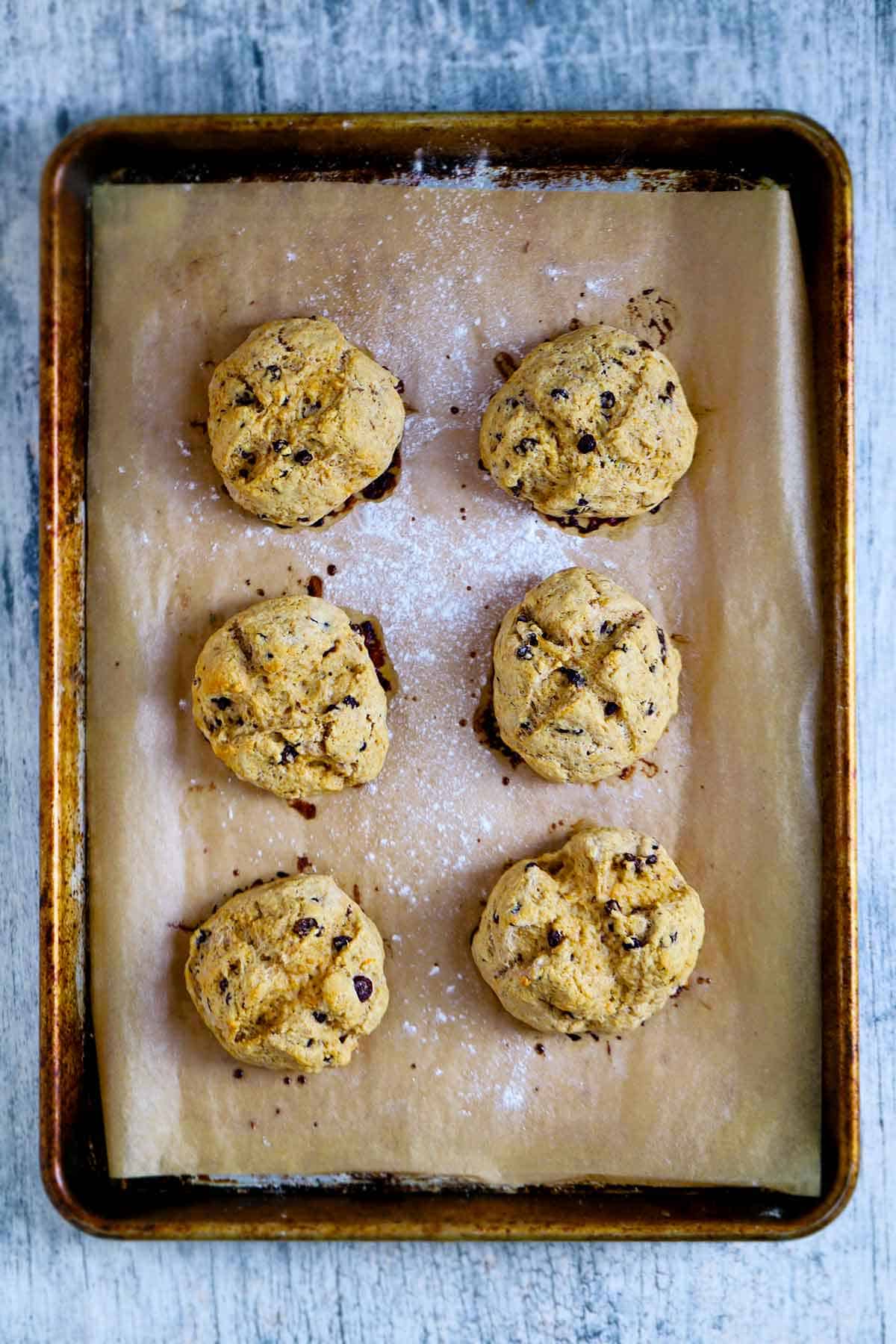 Overhead photo of a sheet pan with six Irish soda bread scones on brown parchment paper.