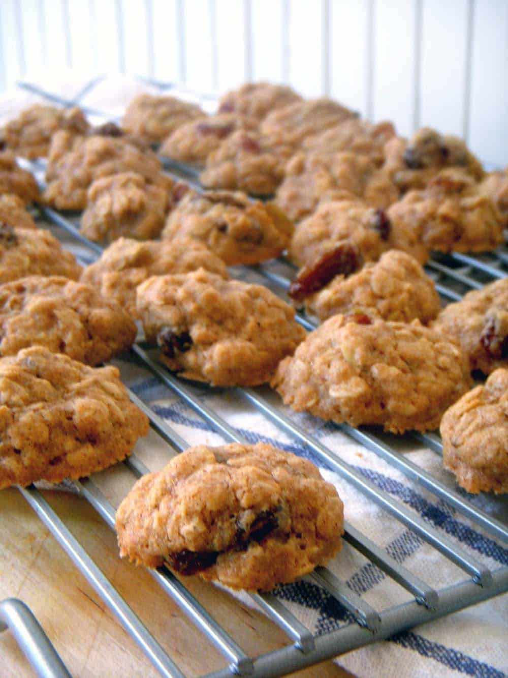 Maple oatmeal raisin cookies spread out on a cooling rack.