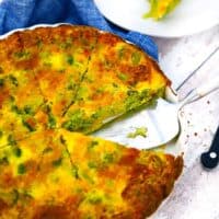 Square photo of crustless broccoli cheddar quiche sliced in a quiche dish.