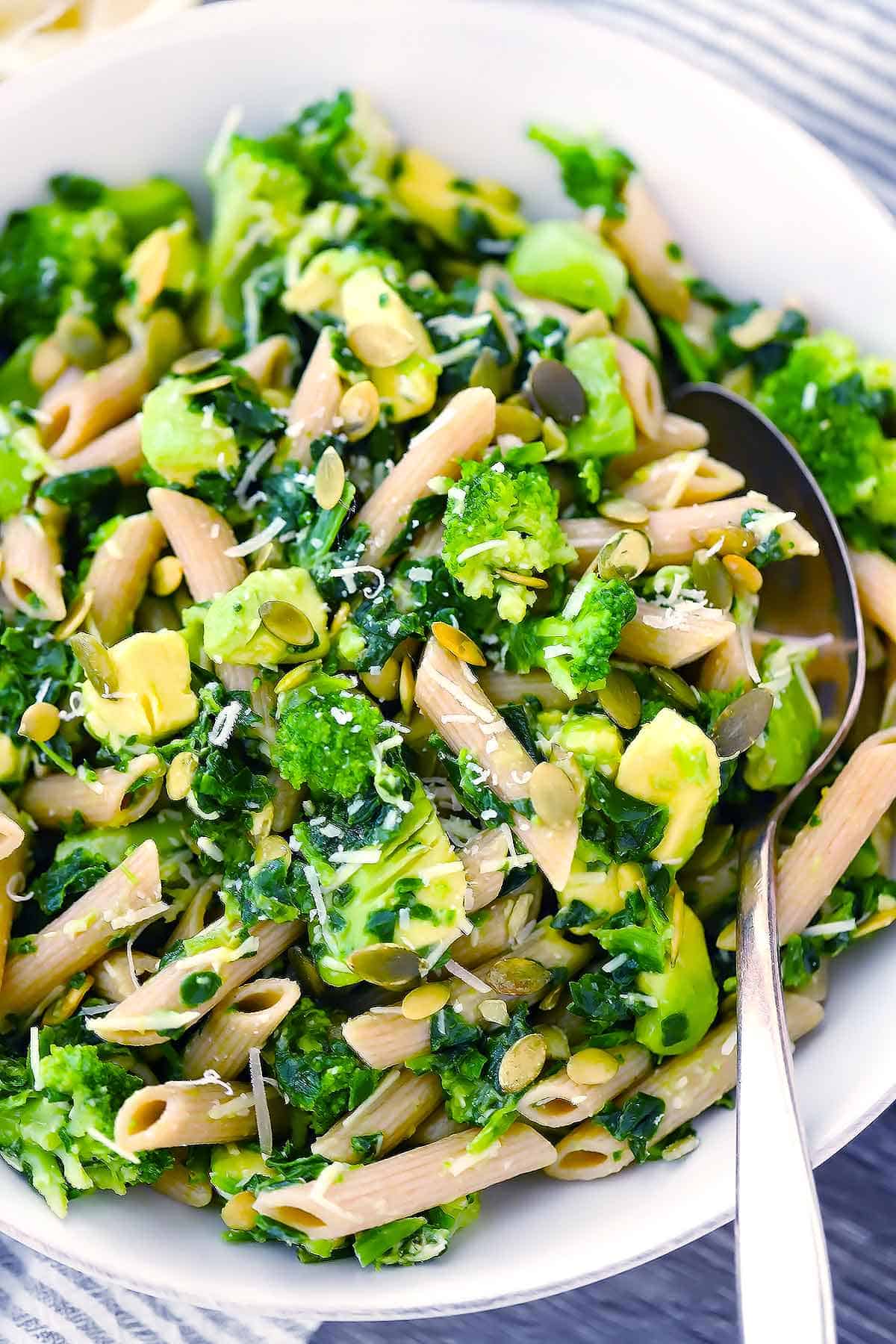 A close up photo of green goddess pasta salad with broccoli and avocado with a spoon.