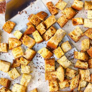 Square photo of homemade croutons on a baking sheet.