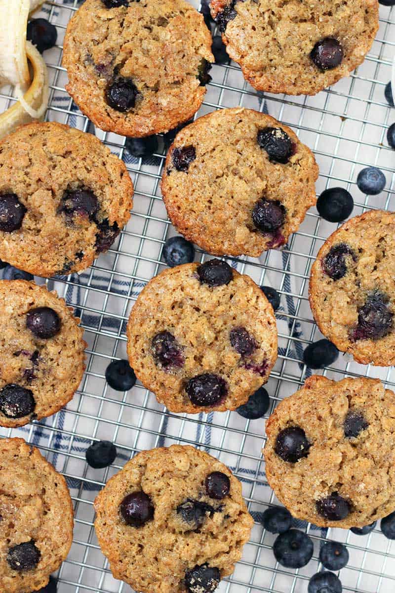 Close up, bird's eye view of muffins on a cooling rack. Blueberries are scattered around.