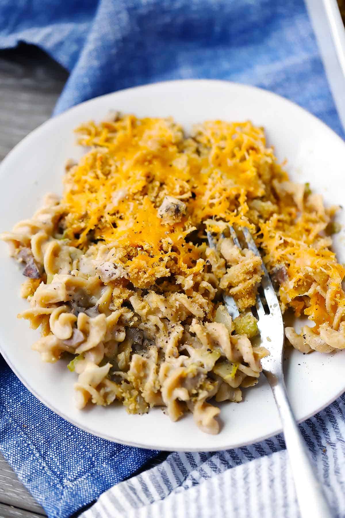 Tuna casserole on a plate with a fork on a blue towel.