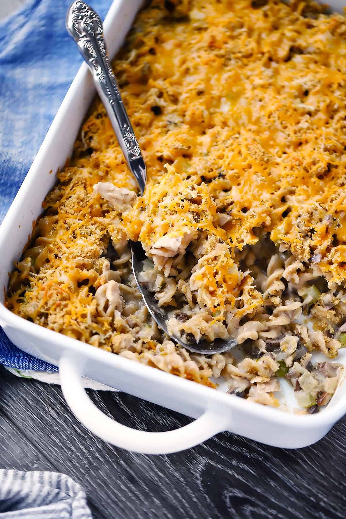 A casserole dish of tuna noodle casserole with a spoon scooping it out.