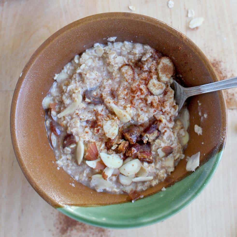 Bird's eye view of a brown ceramic bowl of oatmeal, with a silver spoon sticking out.