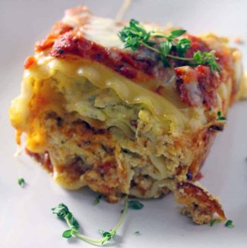 A pesto chicken lasagna roll up on a white plate.