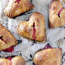 Bird's eye view of strawberry ginger hand pies on parchment paper.