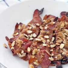 Praline bacon on a white plate, that is on a blue and white checkered cloth.
