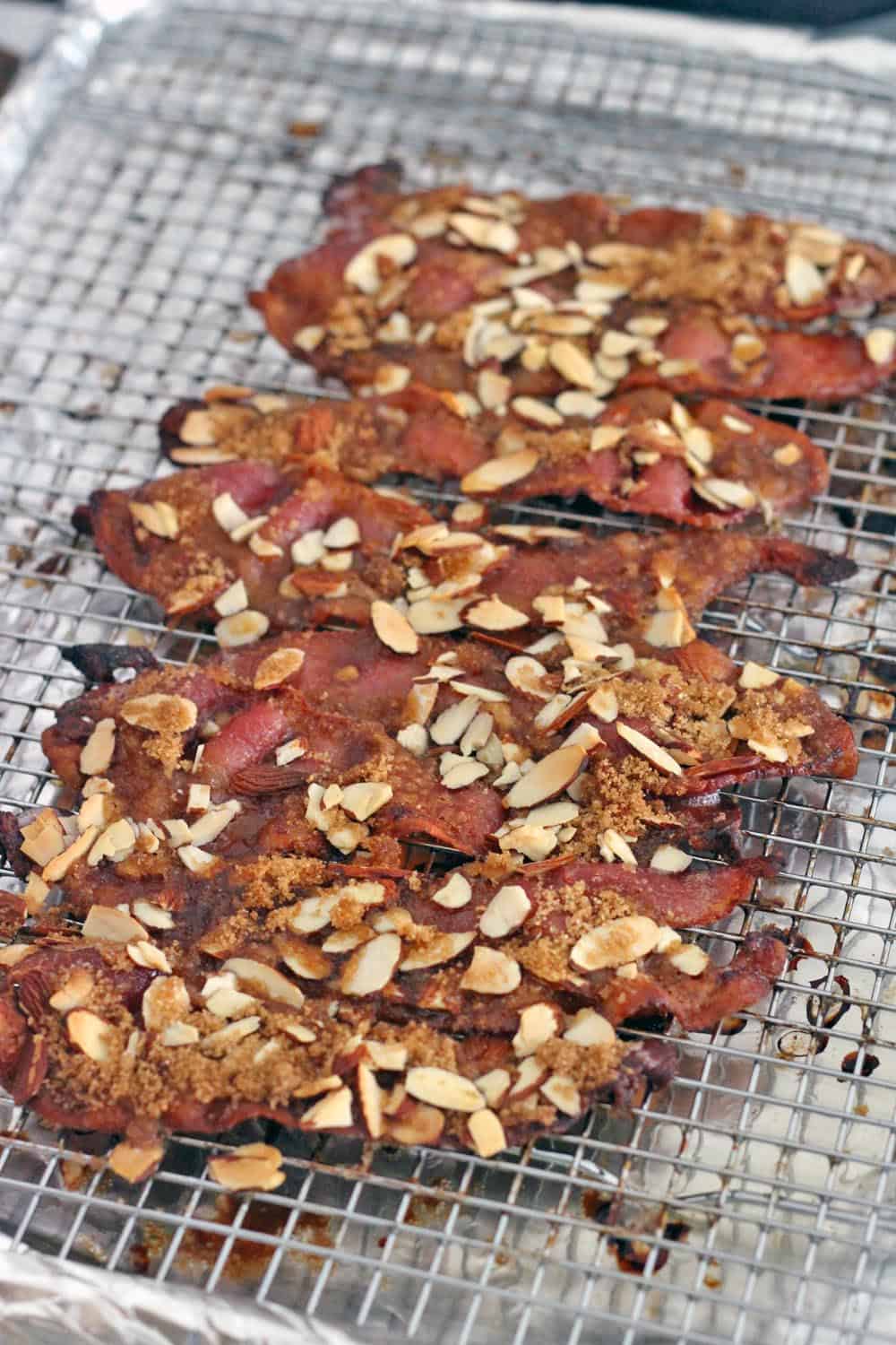 Praline bacon (bacon topped with brown sugar and sliced almonds) on a wire rack.