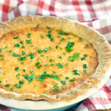 Whole Spicy Southern Tomato and Spinach Pie in a ceramic pie dish, on a red and white checkered cloth.
