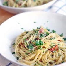 Side view of two white bowls holding Spaghetti alla Carbonara - one in foreground and in focus, the other blurred in the background.