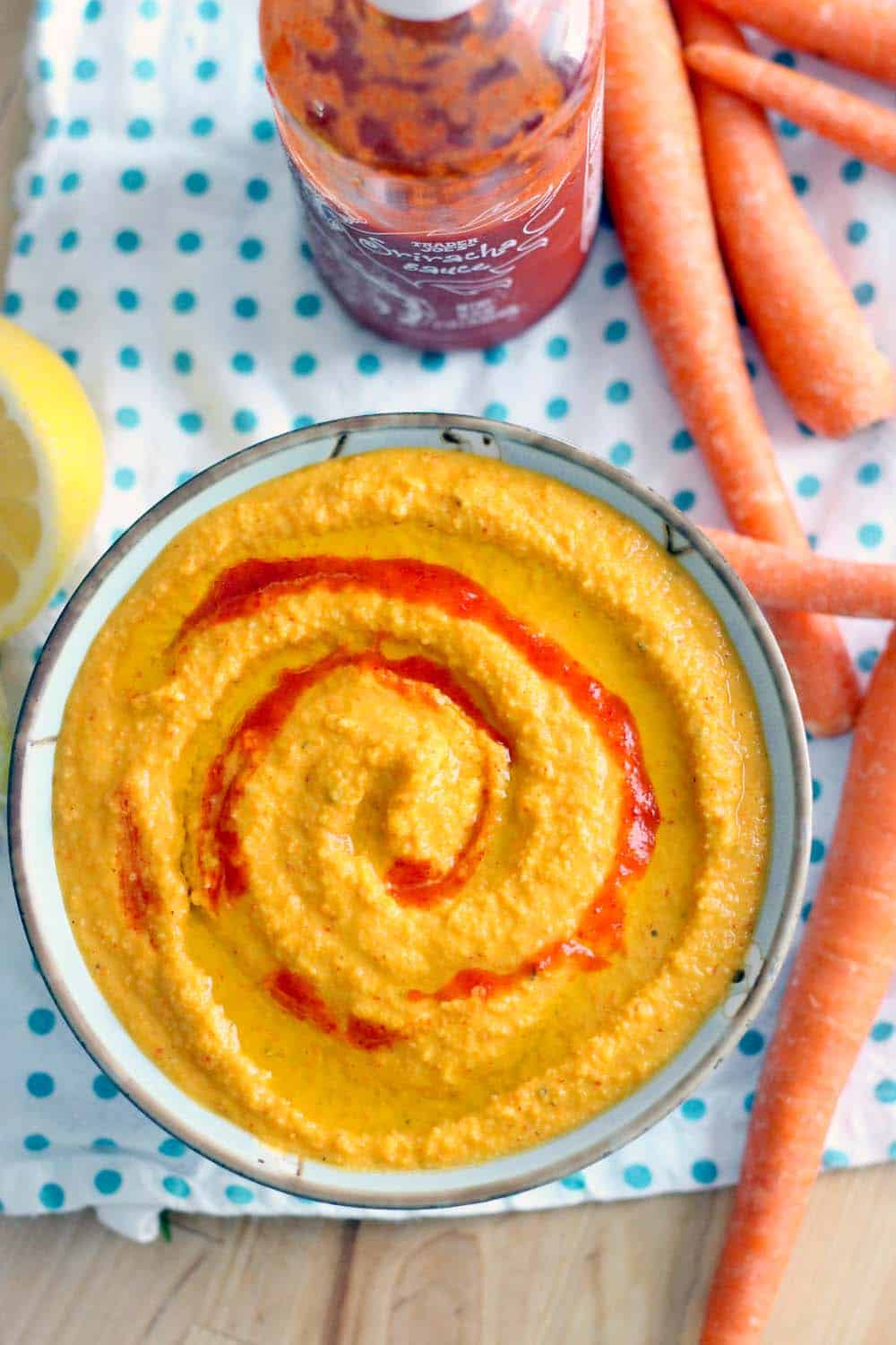 Bird's eye view of Sriracha Carrot Hummus in a bowl, garnished with a swirl of sriracha.