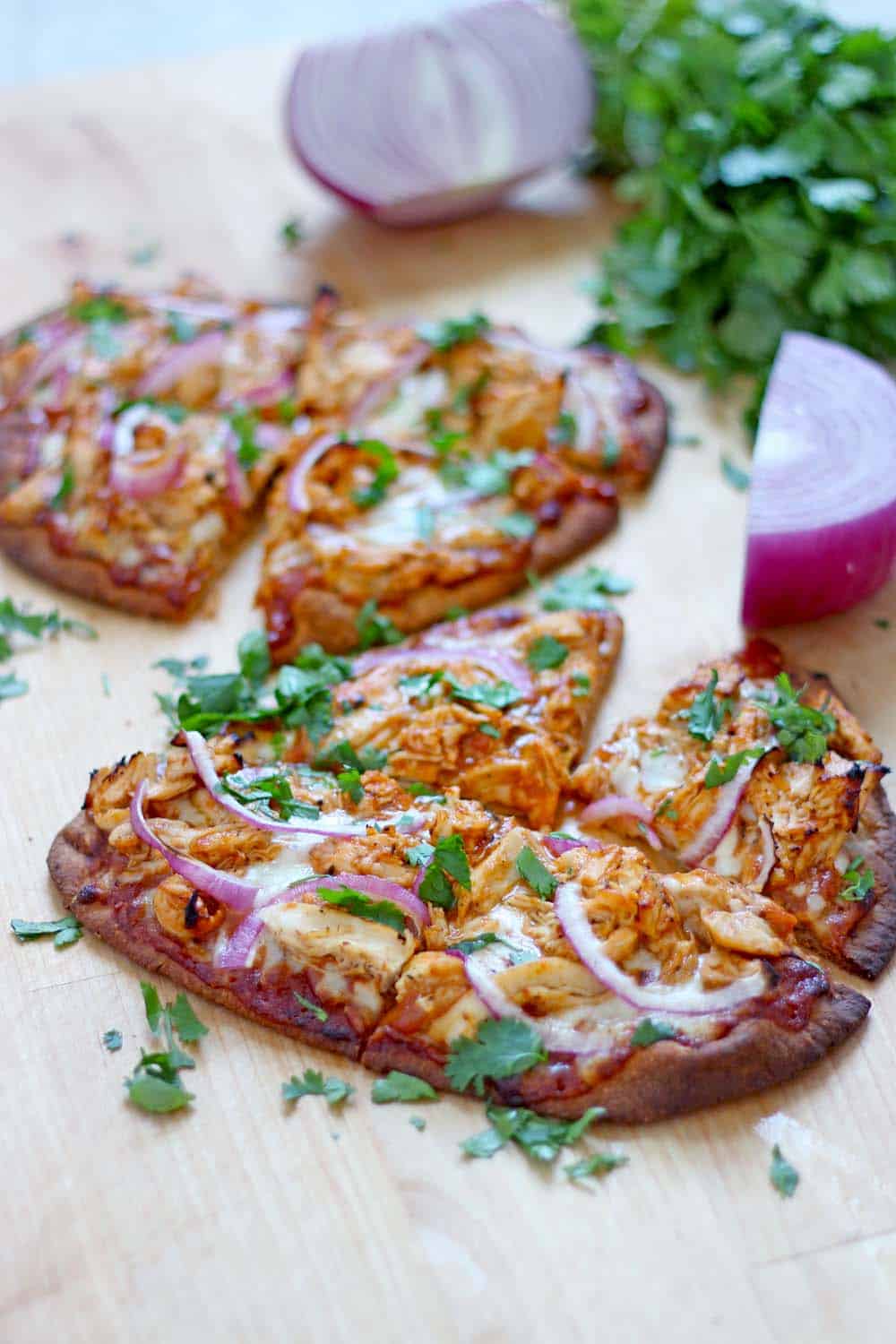 Two BBQ Chicken Naan Pizzas on a wooden cutting board.