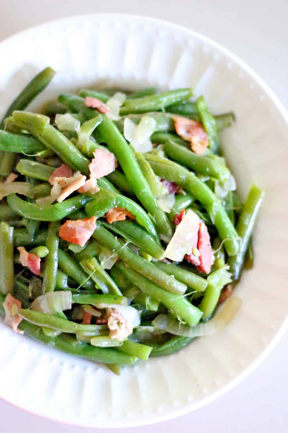 These Southern Style Green Beans are easy and melt-in-your mouth delicious- they're smoky from the bacon and super savory from simmering to perfection in chicken broth! YUM.