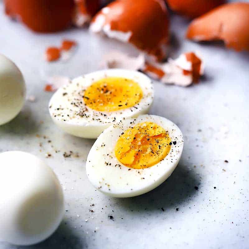 A peeled hard boiled egg cut in half with salt and pepper.