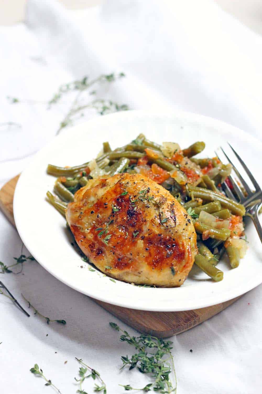 Slow Cooker Greek-Style Green Beans and Chicken thighs is the ULTIMATE one-pot meal: everything cooks in your crockpot at once! Plus, it's cheap, whole30/paleo, low carb, and healthy.