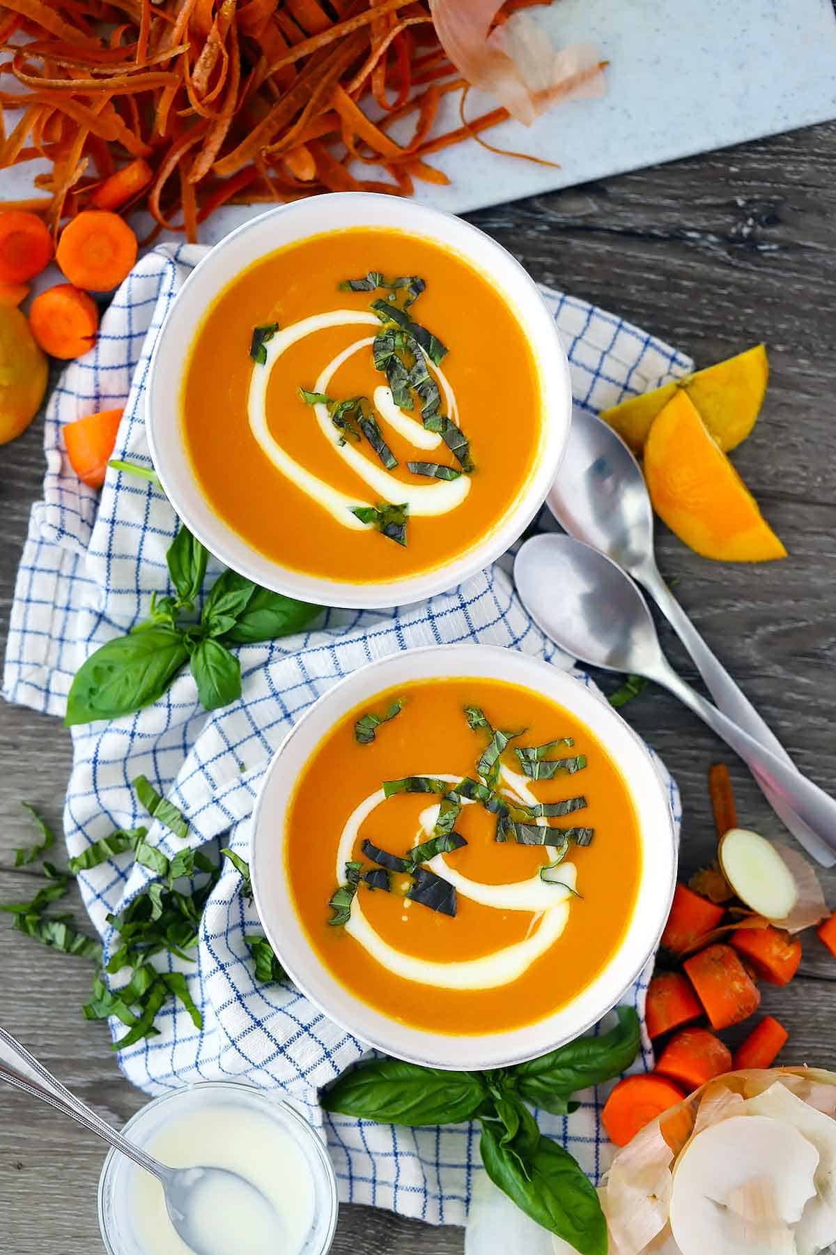 Flatlay of two bowls of carrot ginger soup.