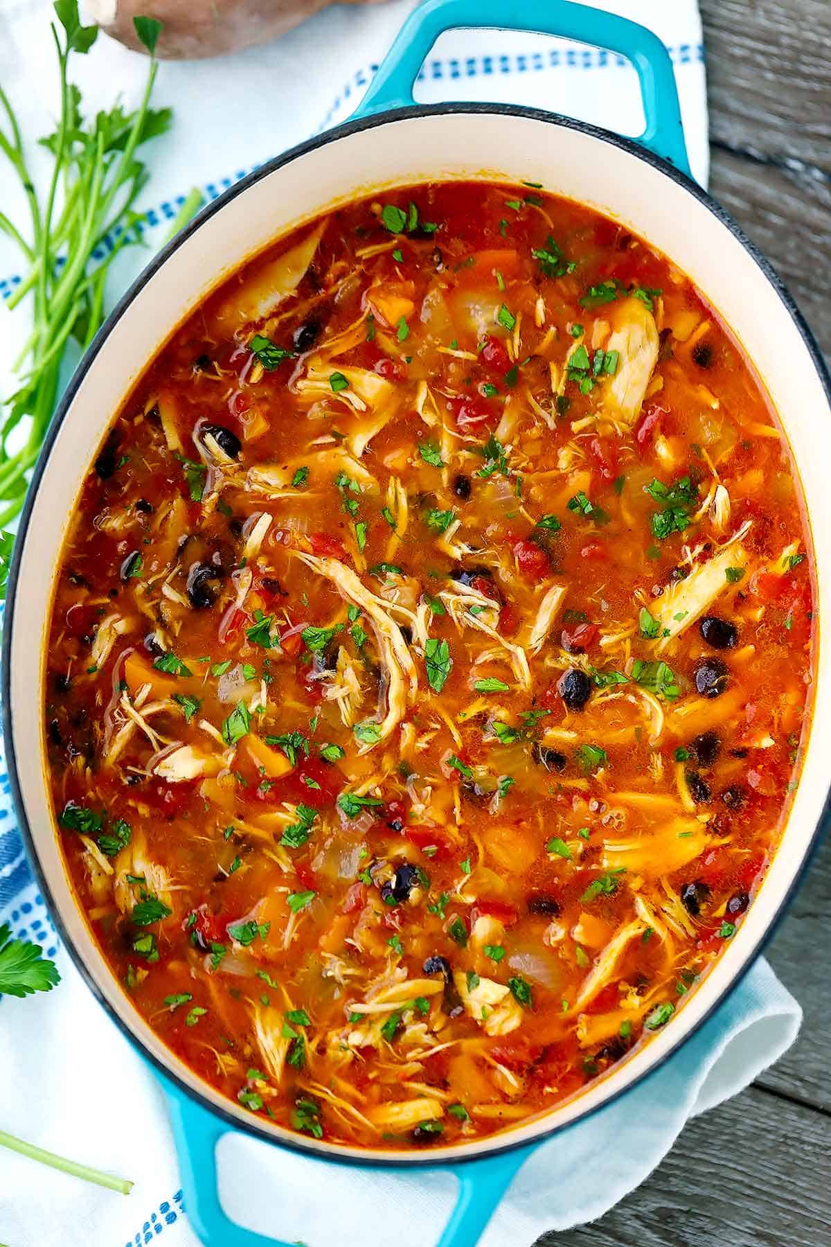 An overhead shot of a blue dutch oven with chicken stew in it.