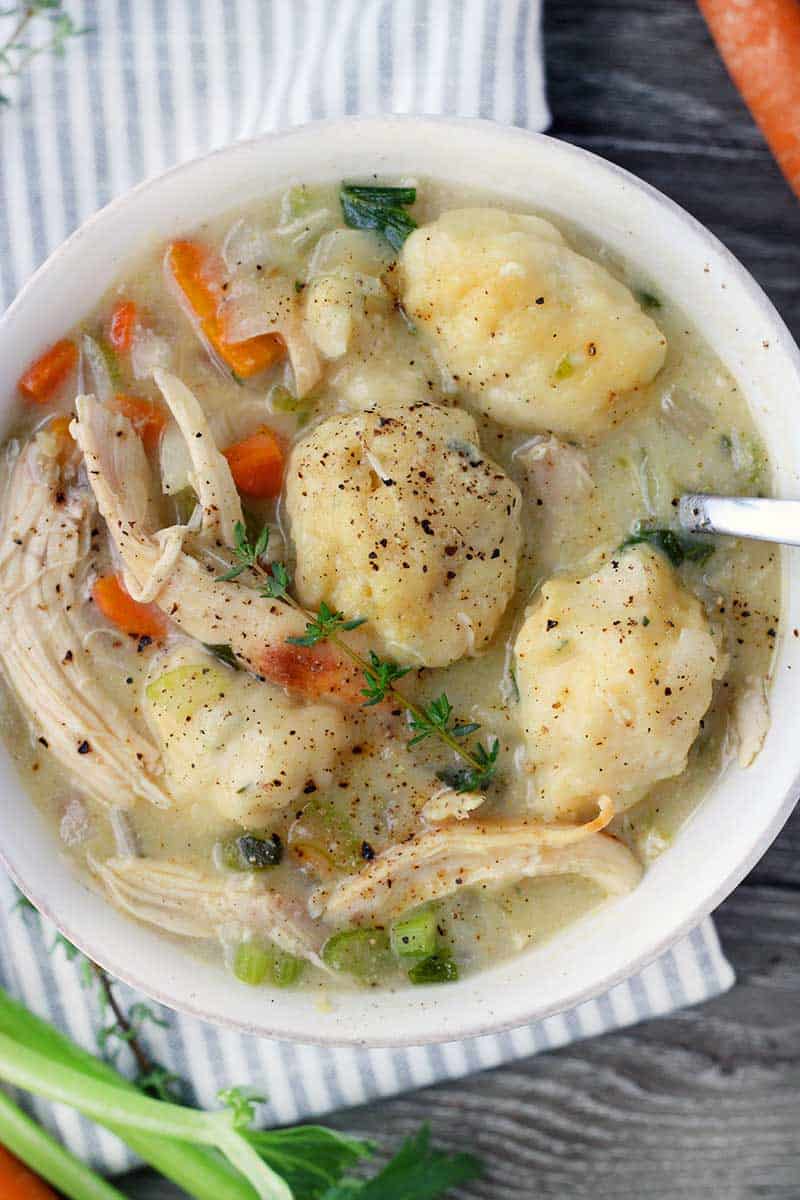 a close up photo of a bowl filled with chicken and dumplings and a spoon