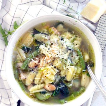 This minestrone soup is PACKED with healthy green veggies, fresh herbs, and topped with a drizzle of olive oil, Parmesan, and pepper. It comes together in 30 minutes and is freezable.