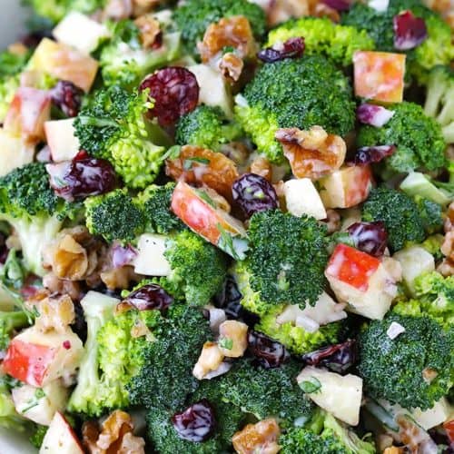 Close up photo of a bowl of broccoli salad with apples, walnuts, and cranberries.
