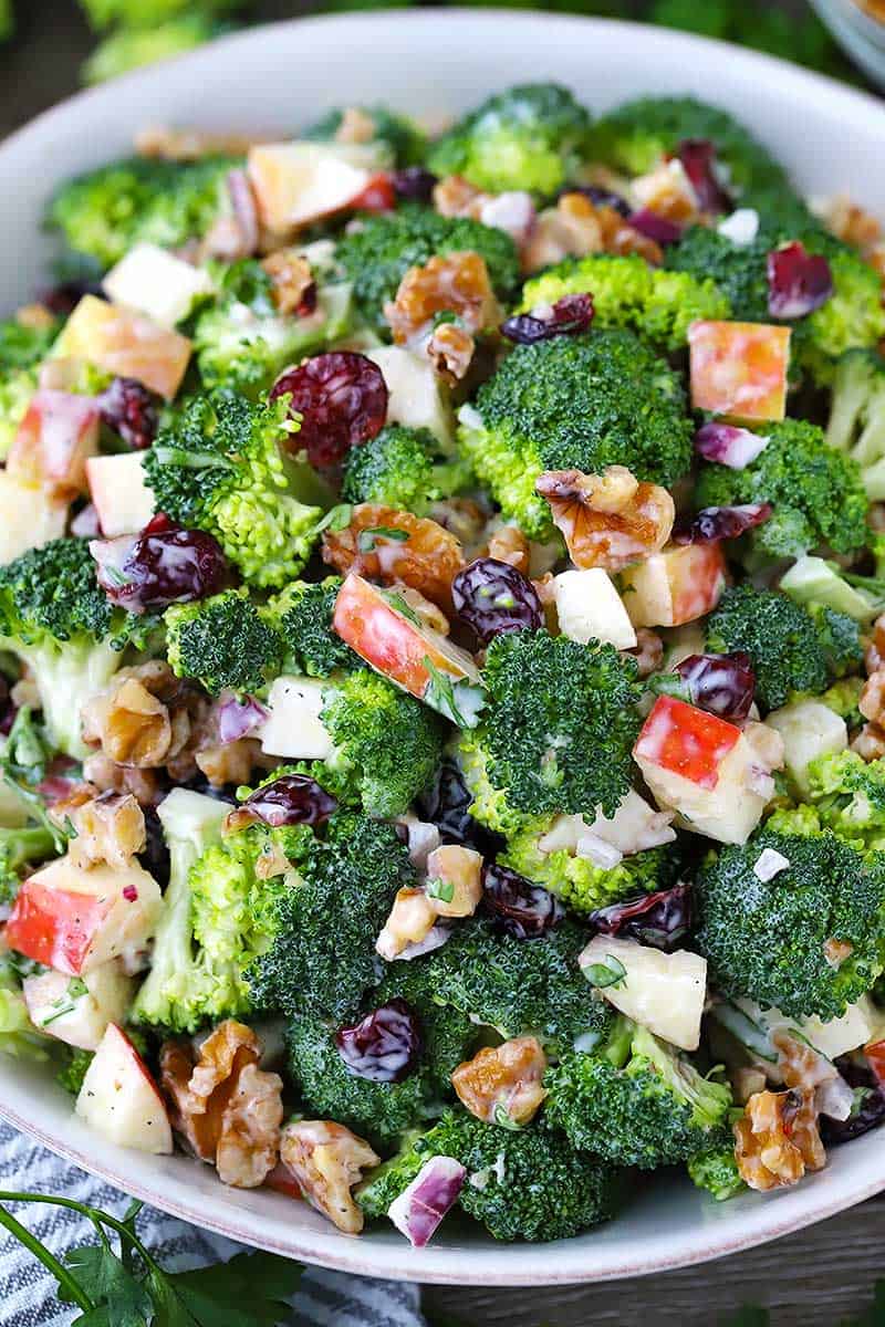 Close up photo of a bowl of broccoli salad with apples, walnuts, and cranberries.