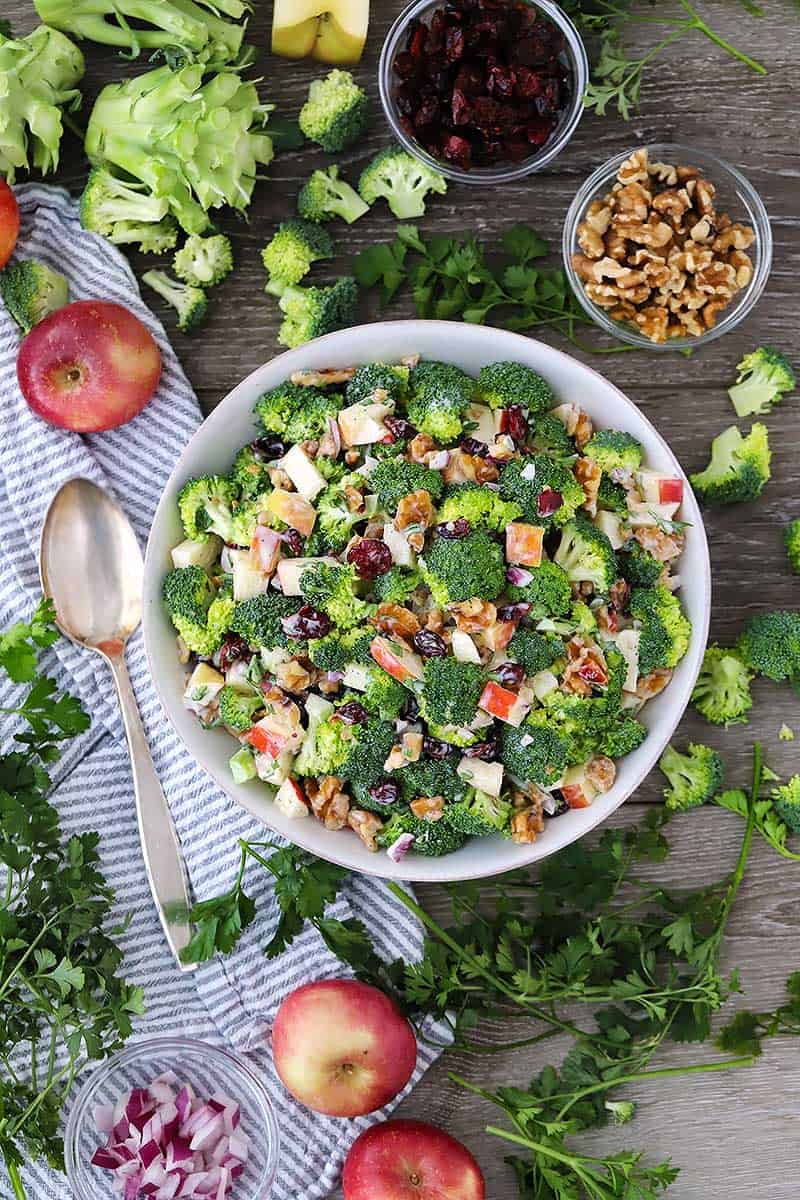 Overhead photo of a bowl of broccoli salad with ingredients around.