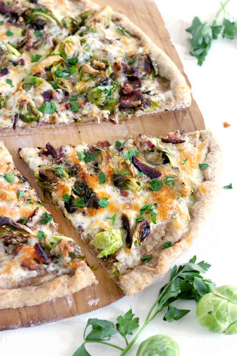 Brussels Sprout and Bacon Pizza is a match made in heaven and a FOUR INGREDIENT recipe! A white pie with seared brussels sprouts, crunchy bacon, and mozzarella cheese baked on a cast iron pizza pan until bubbly with a whole wheat crust. YUM.
