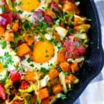 Square overhead photo of corned beef and cabbage breakfast bake with eggs in a cast iron skillet.