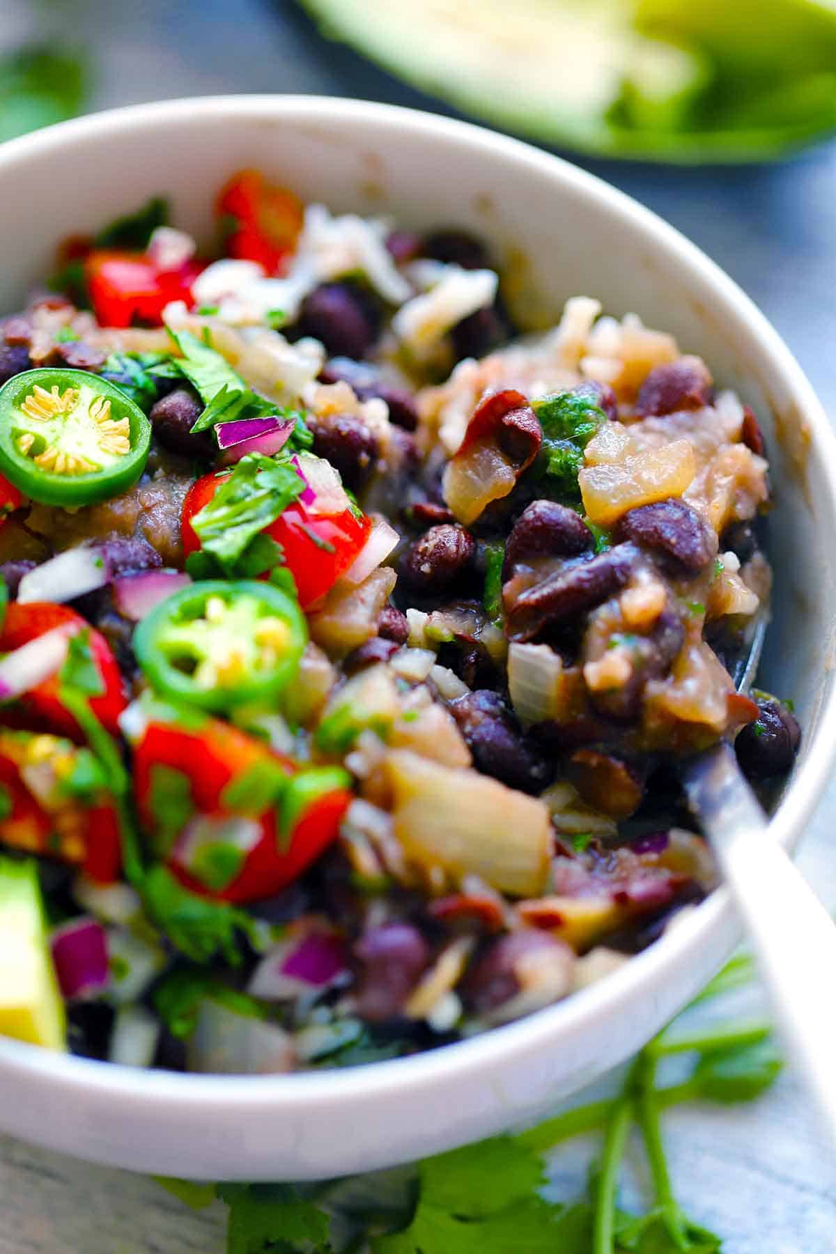 Close up photo of a bowl of black beans and rice with a spoon scooping some out.
