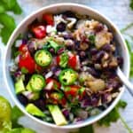 Overhead square photo of a bowl of black beans and rice with a spoon in it.