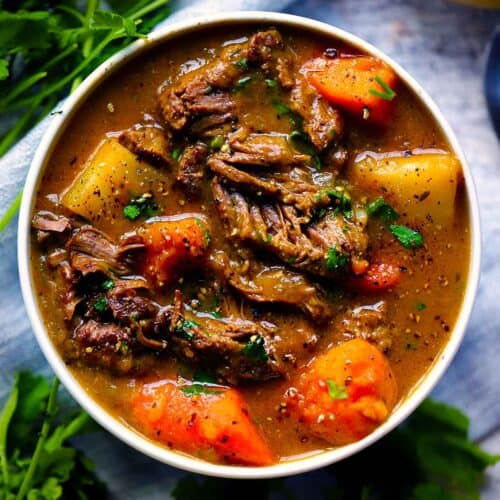 Square photo of an overhead view of a bowl of Irish lamb stew with sweet potatoes, carrots, and white potatoes.