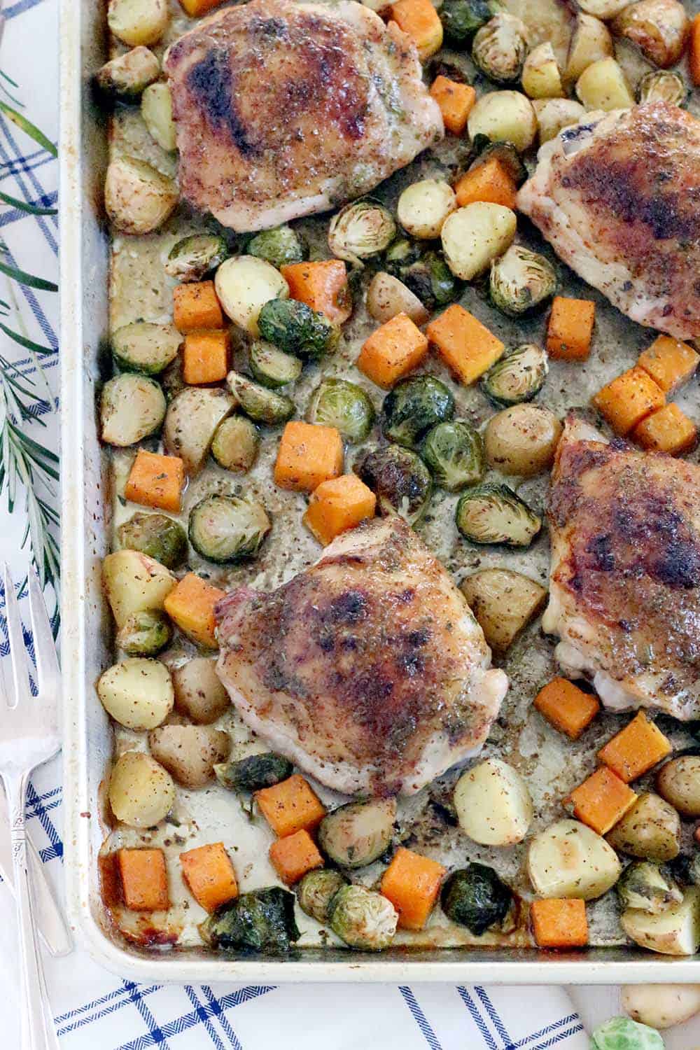 This Maple and Rosemary Glazed Chicken and Fall Veggies Sheet Pan Dinner is an easy way to make a full meal in one pan! Slightly sweet and savory at once, the flavor of the glaze is amazing and coats every single bite. The whole family will love this. #sheetpandinner #paleo #brusselssprouts