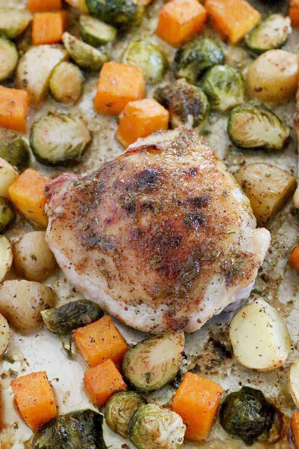 This Maple and Rosemary Glazed Chicken and Fall Veggies Sheet Pan Dinner is an easy way to make a full meal in one pan! Slightly sweet and savory at once, the flavor of the glaze is amazing and coats every single bite. The whole family will love this. #sheetpandinner #paleo #brusselssprouts