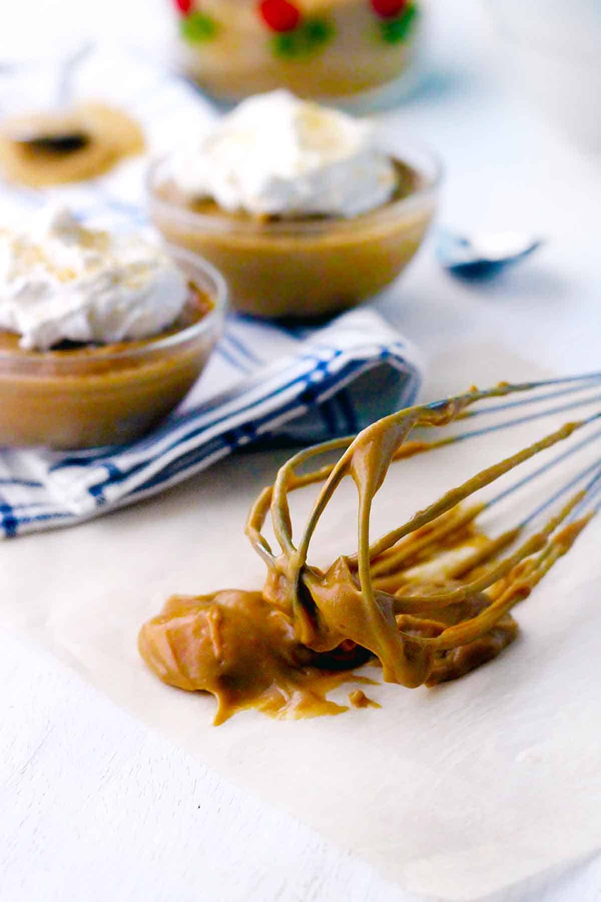 Close up photo of a whisk covered in butterscotch pudding after making it from scratch.