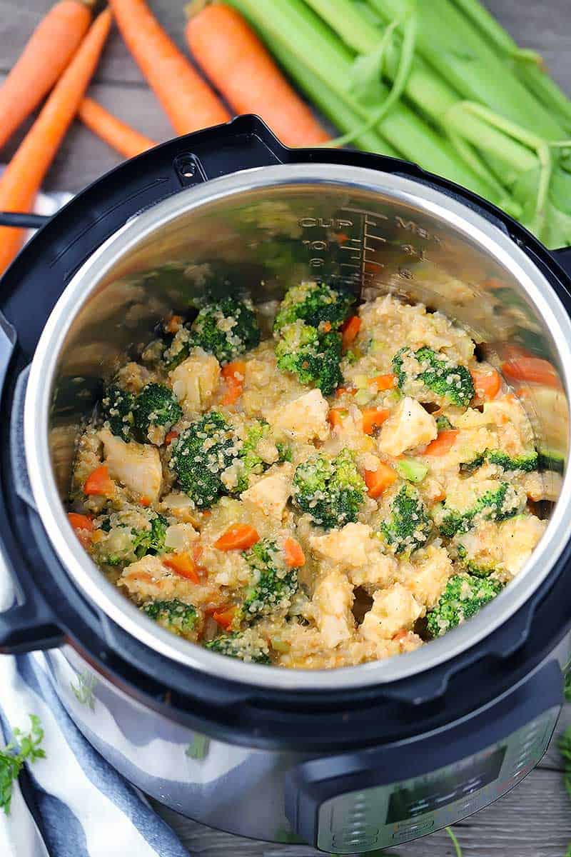 Overhead photo of an instant pot with chicken broccoli and quinoa with celery and carrots around.
