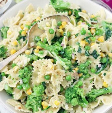 Square photo of creamy lemony pasta salad with spring vegetables with a spoon in it.
