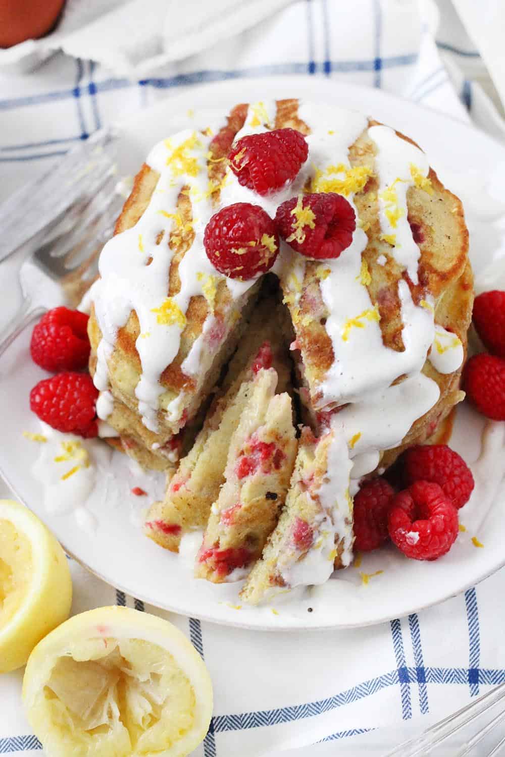 These refined sugar free Lemon Raspberry Pancakes are topped with a creamy Maple Cream Cheese Drizzle. They are light and tart and fluffy- and the red and yellow colors are so pretty! This is the perfect weekend breakfast recipe.