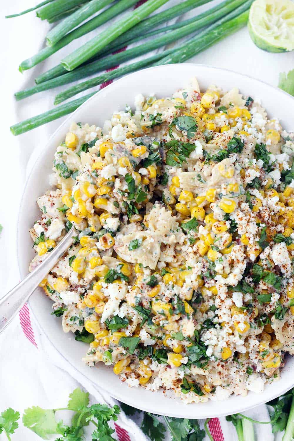 This Mexican Street Corn Pasta Salad is PACKED with sweet corn and tossed in a creamy chili lime dressing. With plenty of queso fresco, bacon, jalapeño, and green onions, this flavor-packed recipe is perfect for a potluck! Can be made with frozen, fresh, or canned corn. Plus, no grilling required! For extra smoky and charred flavor without grilling, the corn is sautéed in bacon fat.