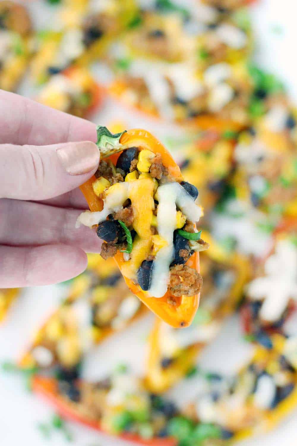 These Taco Stuffed Mini Peppers are the perfect appetizer or light meal! The sweet mini peppers are filled with slightly spicy, taco flavored ground turkey, black beans, and corn for a super fun, low-carb finger food.