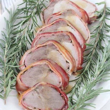 This Bacon Wrapped Pork Loin is a beautiful, impressive, and easy recipe to make ahead of time! Served with a sweet apple cider gravy, this meal is sure to impress at a dinner party or for Sunday dinner.