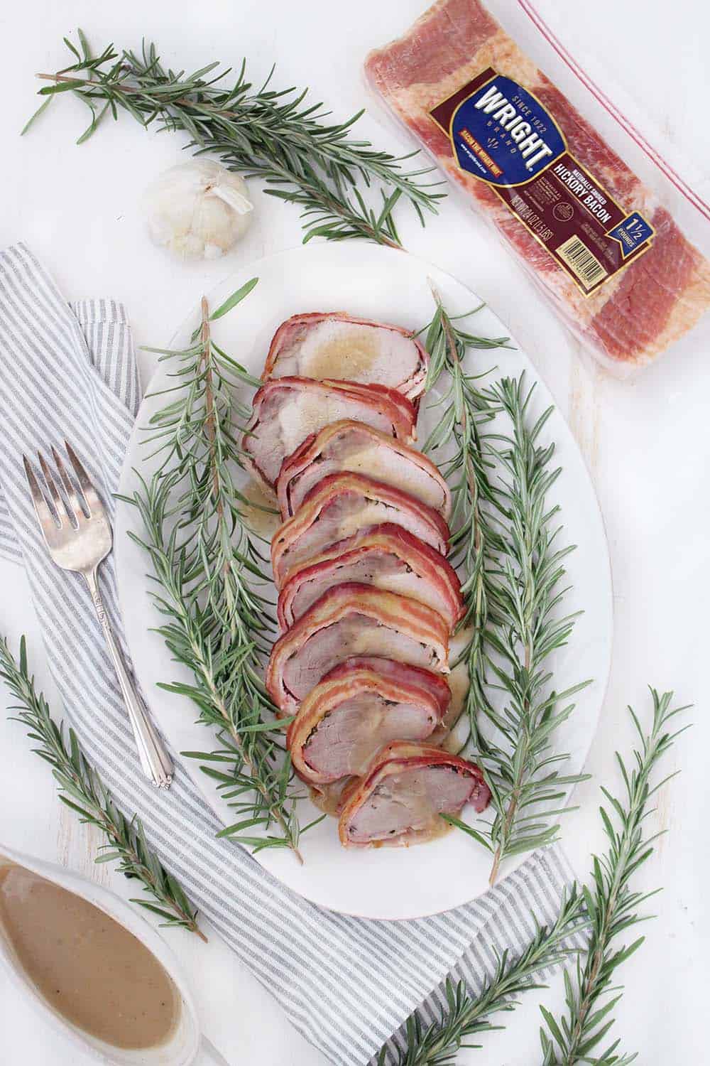 This Bacon Wrapped Pork Loin is a beautiful, impressive, and easy recipe to make ahead of time! Served with a sweet apple cider gravy, this meal is sure to impress at a dinner party or for Sunday dinner.