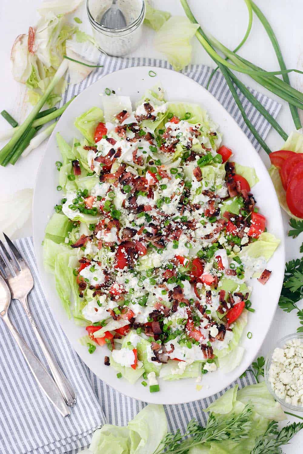 This Deconstructed Wedge Salad recipe has all the classic, refreshing flavor without the need for a knife! Chopped iceberg lettuce is drizzled with homemade blue cheese dressing and topped with crunchy bacon, green onions, and fresh tomatoes.