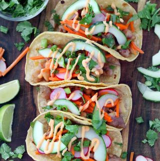 Chicken Banh Mi Tacos are bursting with fresh Vietnamese flavor. Marinated chicken thighs and pickled veggies, wrapped in toasted corn tortillas, topped with a spicy mayo and cool cucumber and herbs! This is an easy, gluten free recipe.