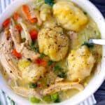 Square photo of chicken and fluffy drop dumplings close up in bowl.