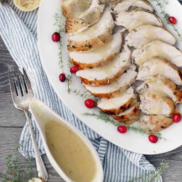 Overhead photo of a platter of turkey and gravy and a gravy boat on the side.